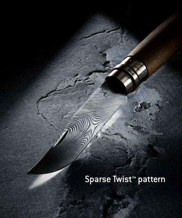 A close-up of a knife with a patterned Damascus-style blade and a brown wooden handle, photographed on a dark textured surface under dramatic lighting. White text at the bottom reads 'Sparse Twist™ pattern'.